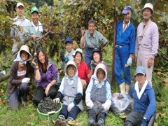 様々な年齢の男女がブドウを収穫して記念撮影をしている写真