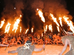 火が付いた長い松明を持った男性たちが円形に並んでいる写真