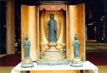 3体の銅造阿弥陀如来及両脇侍立像の写真。奥に大きな像があり、その左右両側に小さい像がある。