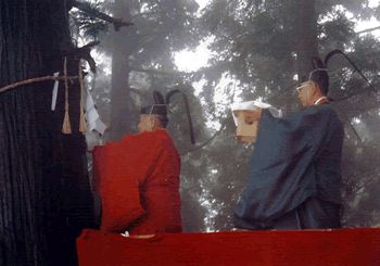 2人の神主がお供え物を持って歩いている写真