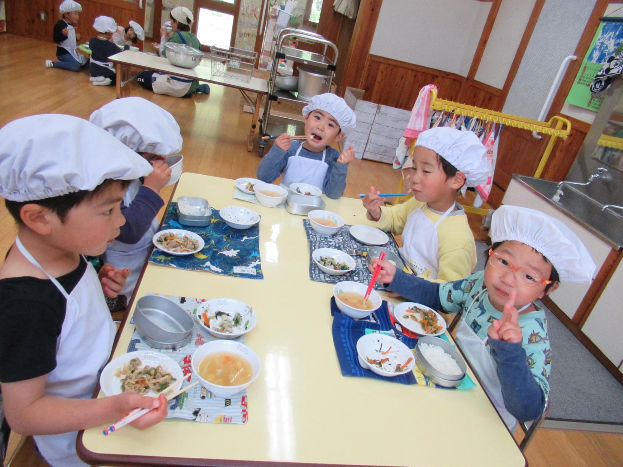 エプロンをつけて給食を食べる園児達の写真