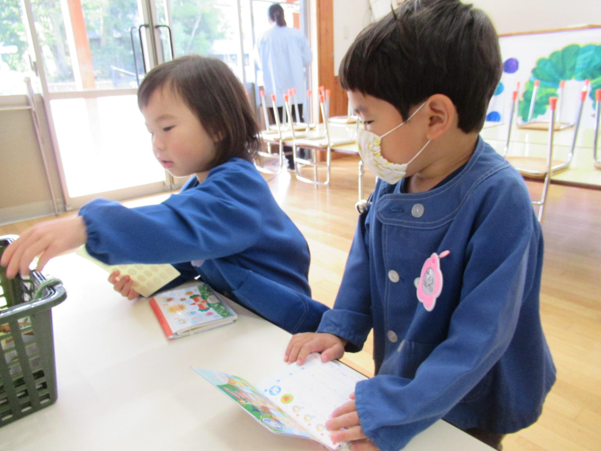 カレンダーにシールを貼る園児2人の写真