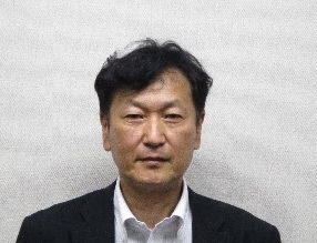 黒のスーツを着た男性が正面を向いている写真