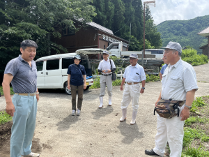 山道に建っている建物近くの道路に集まる5人の男女の写真