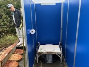 青い壁に囲まれた屋外仮設トイレの写真