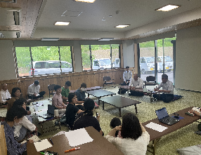 前に座って話す男性2人とそれを座って聞く女性たちの写真