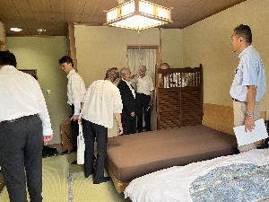 ベッドが置かれた和室を見回る人たちの写真