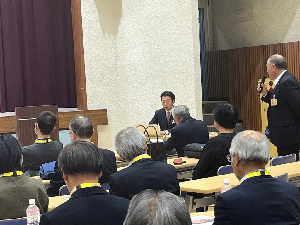 参加者の1人がマイクを持って立ちながら話している写真