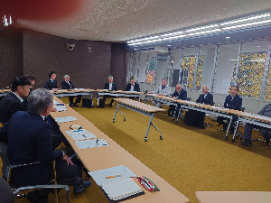 机を楕円型に並べて会議をしている人達の写真