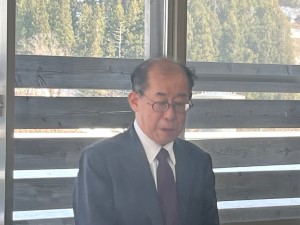 窓際に立っているスーツの男性の写真